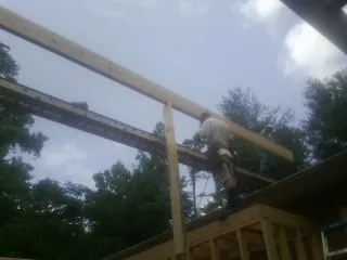 Carpenter setting a ridge beam over a new addition frame — Ice Dam Removal by Roofing Brothers in Midland