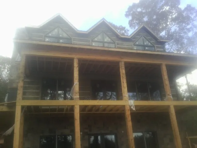 Dormers and porch framing on a large log home under construction — Roof Coating work by our crew in Midland