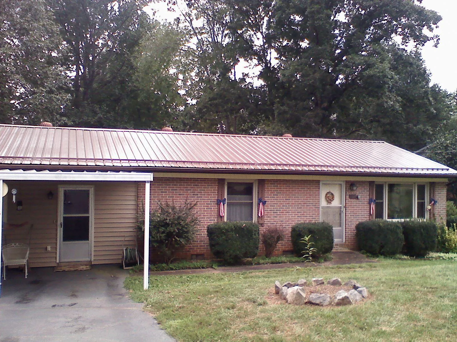 Bronze metal roof and carport on a brick ranch home — Roof Repair work by our crew in Midland
