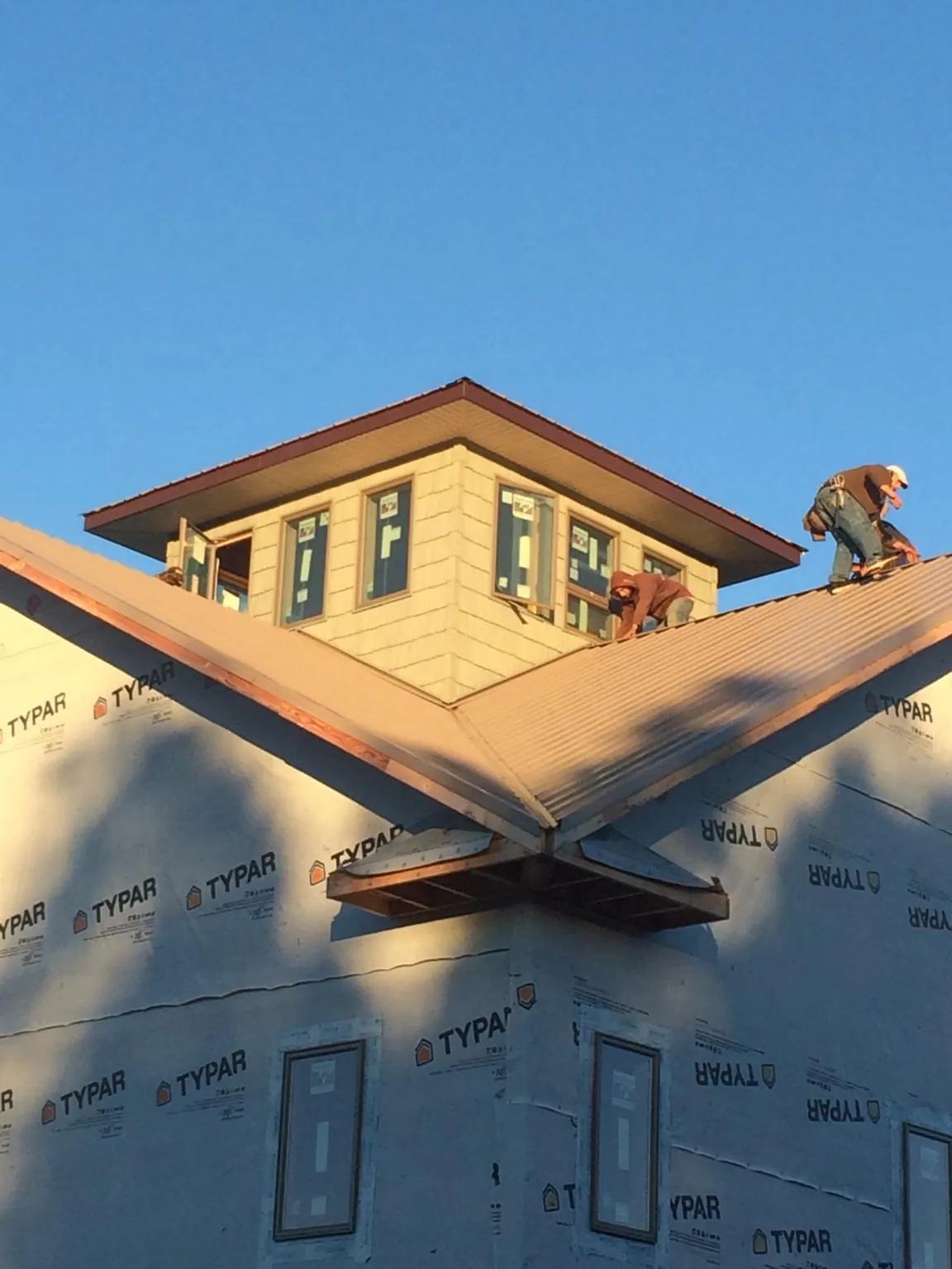 Roofers working around a rooftop cupola on a new metal roof at sunset — Roof Waterproofing in Midland by Roofing Brothers